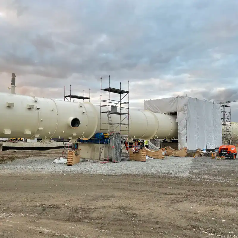Large white industrial pipe with scaffolding and protective covering.