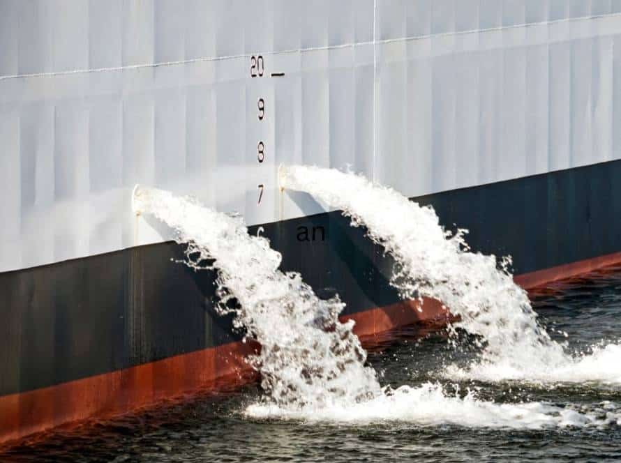 Water discharge from ship's hull with measurement scale.