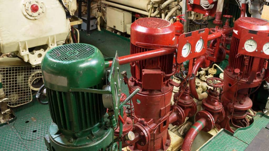 Red and green fire pumps with gauges on a ship.